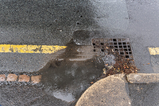 Partially blocked storm drain restricting rainwater drainage during rainfall