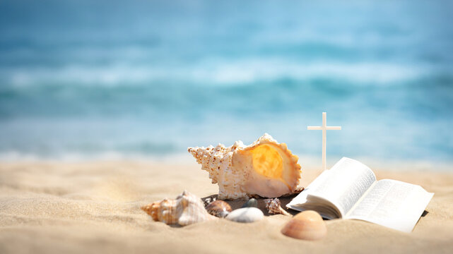 Summer camp background featuring the Cross of Jesus Christ, a Bible, and a seashell on a sandy beach, church summer Bible school, summer retreat, and concept
