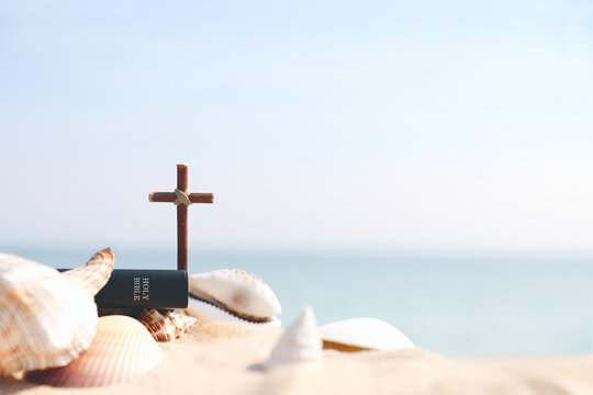Summer retreat background featuring a Bible and the Cross of Jesus Christ on a sandy beach, church summer Bible school and summer camp concept
