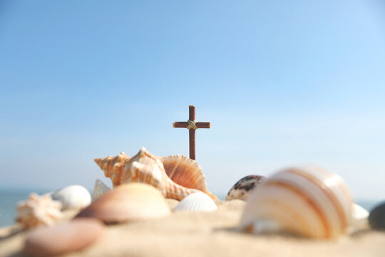 Summer camp background featuring the Cross of Jesus Christ and a seashell on a sandy beach, church summer Bible school and summer retreat concept
