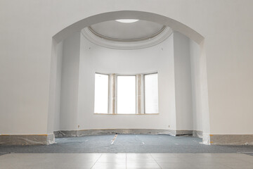Empty room in an old building in the ground floor. Renovation work like painting the wall with white color. Construction site with masked flooring and a fleece cover. © Felix Geringswald