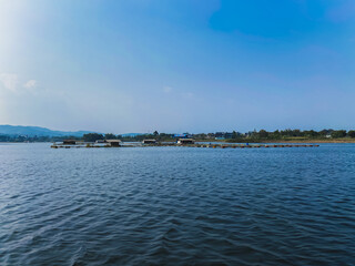 Floating fish cages and small huts on a calm lake under a clear blue sky © Stora Space