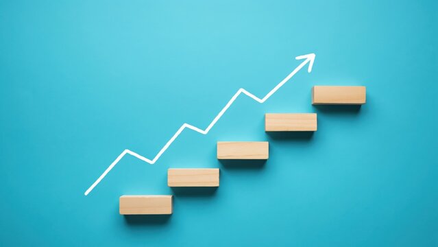 Wooden blocks arranged as stairs with white upward arrow on blue background symbolizing progress