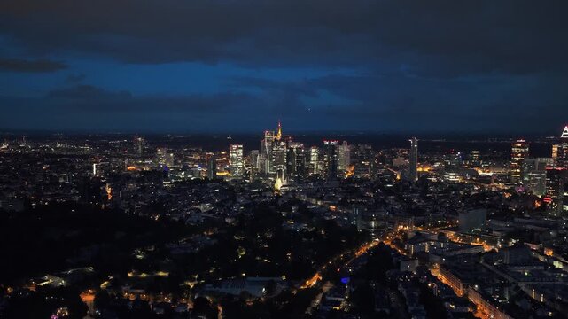 Luminous Frankfurt Germany cityscape at night showing downtown skyline with illuminated financial district skyscrapers and urban city lights against dark blue sky