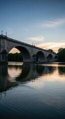 Fototapeta premium Majestic Stone Bridge Reflecting in Calm River at Sunset with Beautiful Sky.
