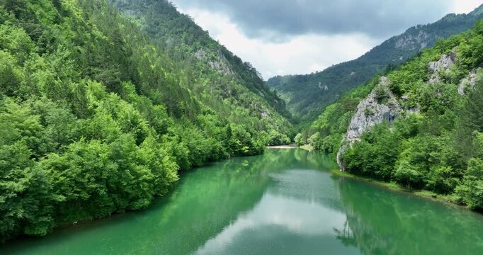 Drone flying forward over green river in a mountain canyon. Drina river, Bosnia