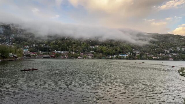 boats at the nainital lake with clouds over the hill above mall road