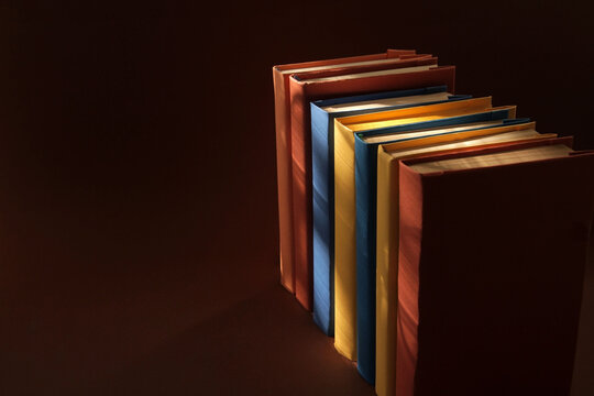 Concept: Books arranged in a row with colorful covers on colorful paper backgrounds. Color symbolism characterizes the diversity of information topics. Paper with popular complementary colors.