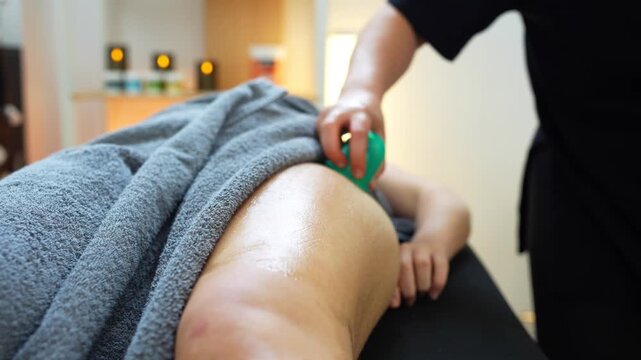 Female therapist applying a suction cup on a woman's leg for muscle relaxation and skin treatment