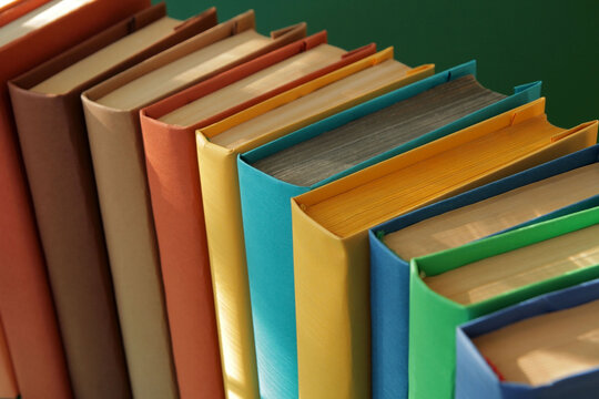 Concept: Books arranged in a row with colorful covers on colorful paper backgrounds. Color symbolism characterizes the diversity of information topics. Paper with popular complementary colors.