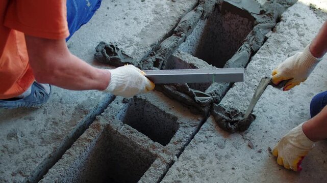 Workers filling floor block openings with mortar