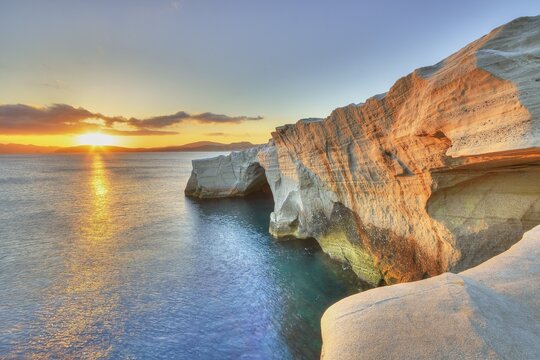 Morning light, sunrise, sun as star, orange-red sky, tuff rocks in morning sunlight, HDR, single grey clouds, Sarakiniko Beach, Milos Island, Cyclades, Greece