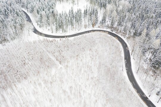 Aerial view of a winding country road and forest in the snow, between Eppendorf and Leubsdorf, Central Saxony, Germany