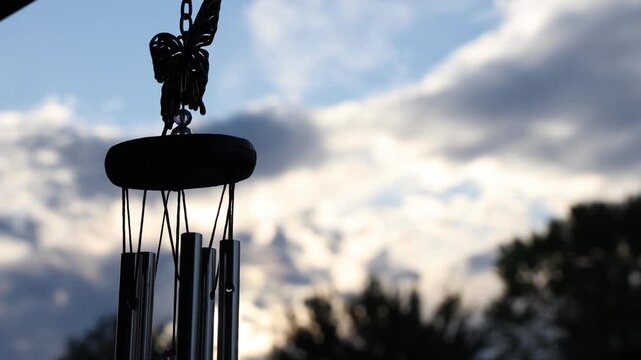 Close-up of a wind chime with a butterfly ornament against a cloudy sky