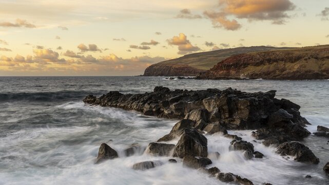 Rocky volcanic coast with surf in evening light, view of the cliffs of the Poike Peninsula, Easter Island, Chile
