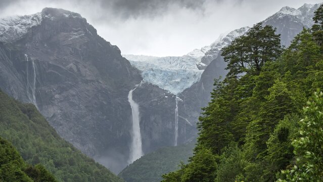 Ventisquero Colgante hanging glacier with cascading waterfall over steep rock face, surrounded by snow-capped mountain peaks and subpolar rainforest, Queulat National Park, Ays&eacute;n region, Chile
