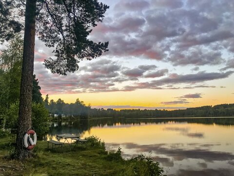 H&auml;llefors, &Ouml;rebro l&auml;n, Sweden, A peaceful lake at sunset with trees and calm water reflecting the sky