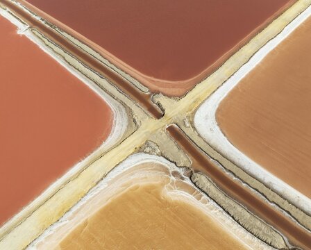 Saline ponds at the Bonanza salt works near Sanl&uacute;car de Barrameda. The reddish colour depends on the level of salinity and is directly caused by the algae Dunaliella salina and brine shrimp. Aerial view. Drone shot. C&aacute;diz province, Andalusia, Spain