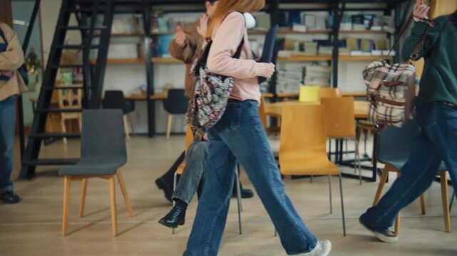 Group of people interacting in a library setting while one person sits and smiles with a folder in hand