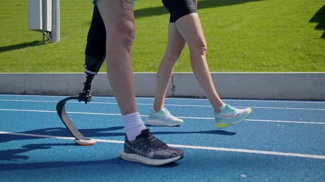 Man athlete with bionic leg prosthesis walks near instructor