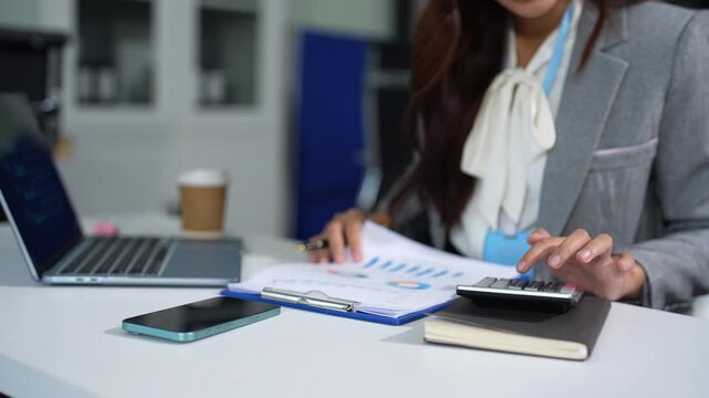 Business woman working on laptop and accounting financial report, accountant using calculator to calculate tax refund at office.
