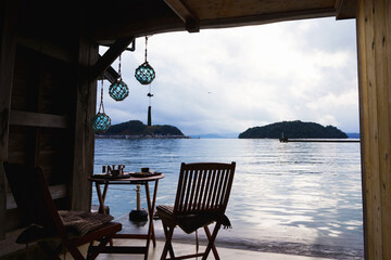 Cozy seaside terrace interior with wooden chairs and glass fishing floats hanging © 현태 박