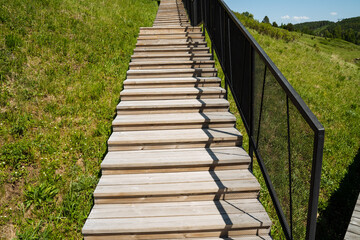 Obraz premium Wooden staircase detail. Rhythmic shadows on wooden stairs. Close up of wooden steps with shadows emphasizing grain. Detailed view of wooden steps highlighting grain and shadow patterns