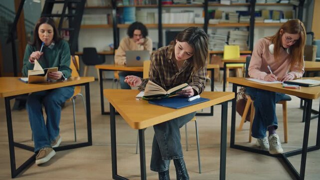 Students read books and write notes in a library during a study session in the afternoon hours on a weekday