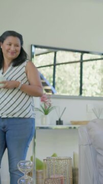 Vertical video: Stepping woman in striped top with white mug smiling at home from mirror reflection