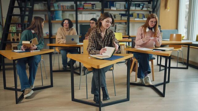 Group of students studying in a library with books and laptops during daytime