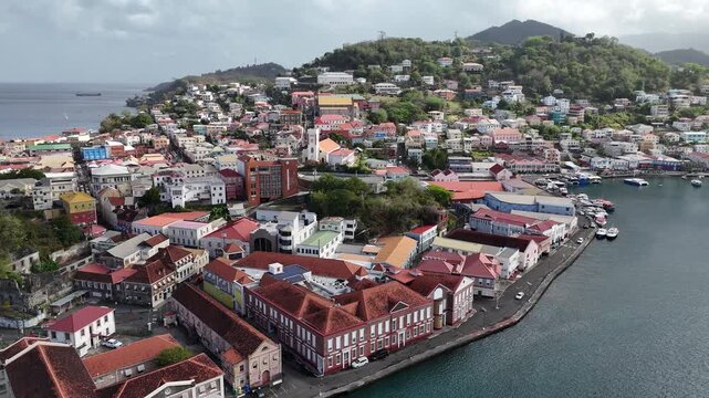 drone fly above colonial buildings and narrow urban streets wrapping around the historic waterfront of Carenage harbor, Grenada