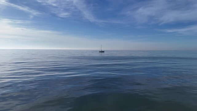 Clean aerial composition of solitary sailboat on smooth water.
