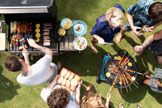 Top view of a diverse group enjoying a barbecue in a sunny backyard.