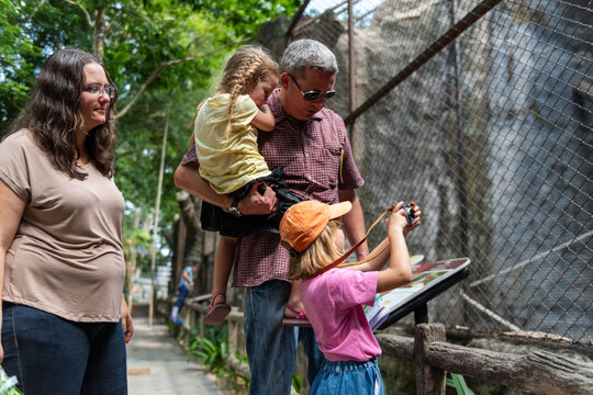 Family with children observing animals at a zoo on a sunny day