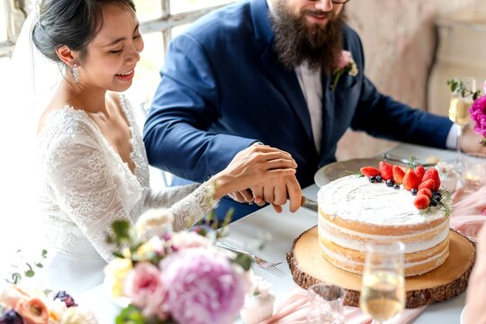 Joyful couple cutting wedding cake