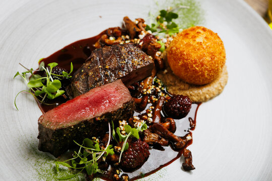 Luxury steak dinner with crispy croquette and berry reduction