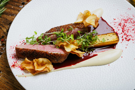 Gourmet duck meat with crispy vegetable chips and herbs