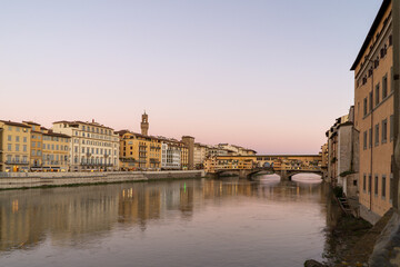 Fototapeta premium The iconic Ponte Vecchio bridge spans the Arno River in Florence, Italy, illuminated by the soft glow of twilight