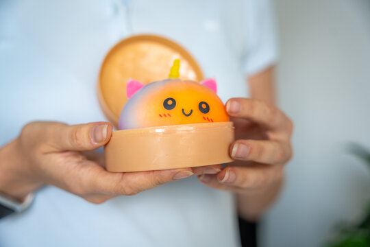 Woman opening container with cute unicorn squishy bun toy. Stress relief toy and sensory fidget concept