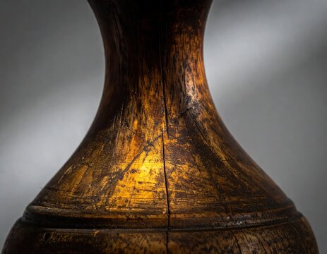 Close-up of an antique wooden vase with intricate carvings and a warm glow.