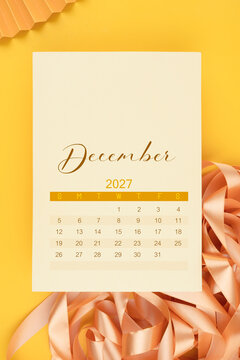 December 2027 calendar page with yellow ribbon on yellow background.