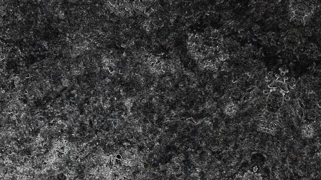 Dark marbled textured surface with cloudy patterns, scattered marks, and rugged organic appearance. Grunge texture background animation.