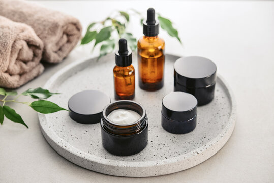 Natural skincare and beauty treatment concept with amber glass cosmetic containers arranged on a round tray.