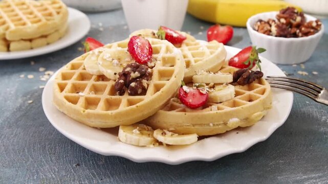 Healthy Gluten Free Banana Oats Waffles with ingredients for cooking, fresh banana, strawberry slices, nuts and honey. Homemade belgian waffles recipe without flour and sugar, balanced proper nutritio
