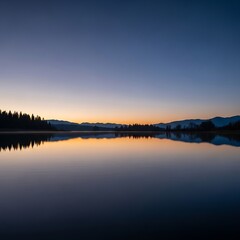 Fototapeta premium Serene sunrise over calm lake with misty mountains.