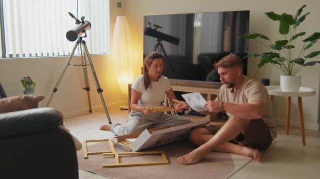 Young adult couple are working on putting together a piece of furniture in their living room