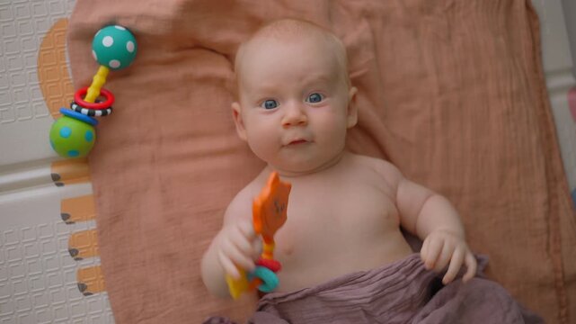 Three month old baby moving arms and legs on soft mat.