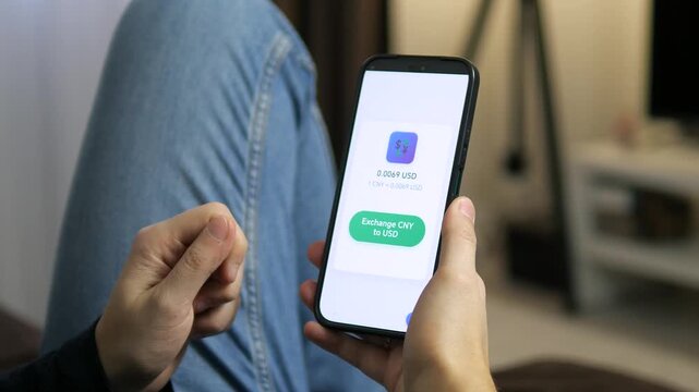 Viewing a currency exchange screen on a smartphone. The display shows a conversion rate of 0.0069 USD for 1 CNY. Perfect for fintech apps, foreign exchange, and digital banking visuals.