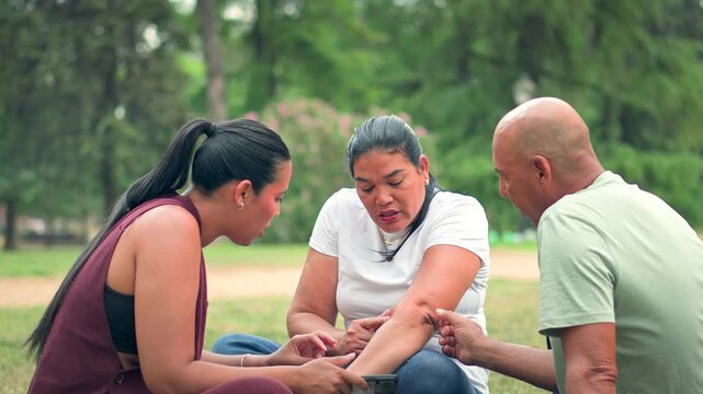 Parents and daughter checking mother&rsquo;s arm after insect bites in park