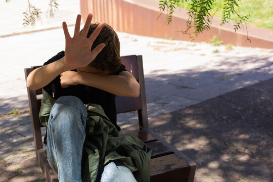 Lonely teenager showing a stop sign sitting on the bench